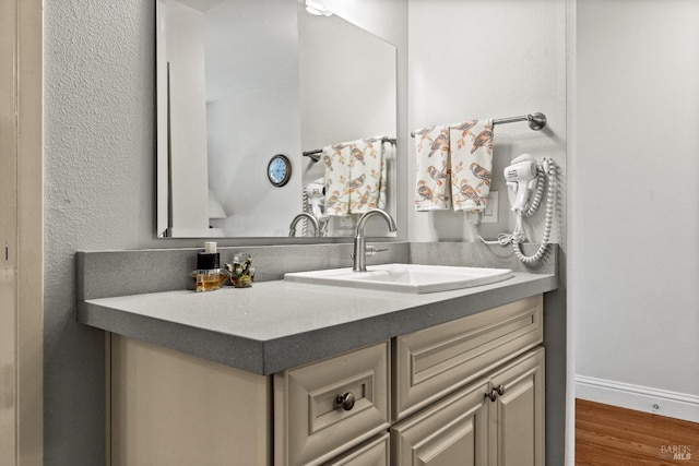 bathroom with wood finished floors, vanity, and baseboards