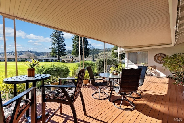 wooden deck with outdoor dining space and a lawn