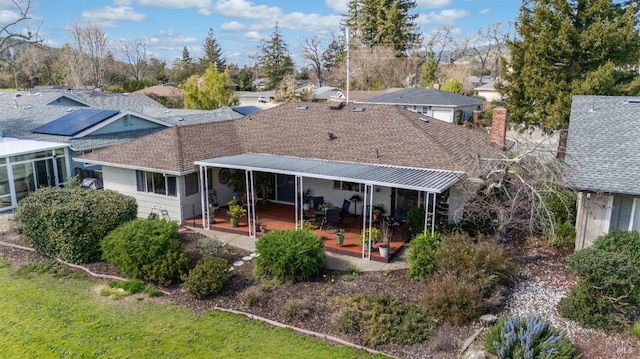 rear view of house with a patio and roof with shingles