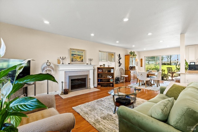 living room featuring a fireplace with flush hearth, wood finished floors, and recessed lighting