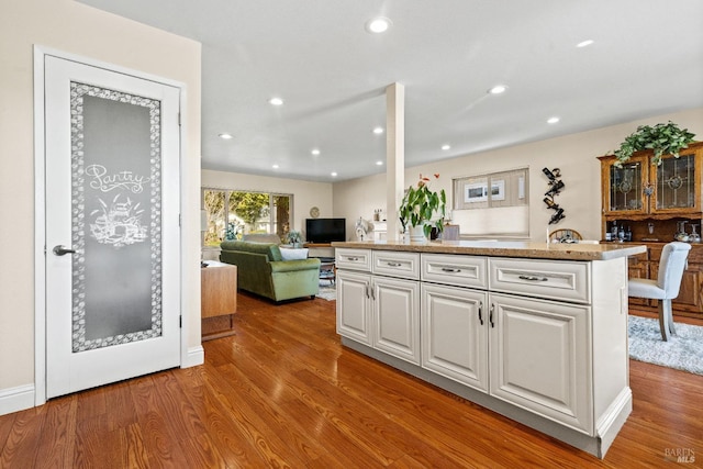 kitchen with recessed lighting, open floor plan, white cabinets, and wood finished floors