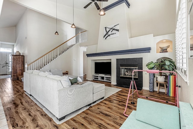 living room with a tile fireplace, plenty of natural light, stairway, and wood finished floors