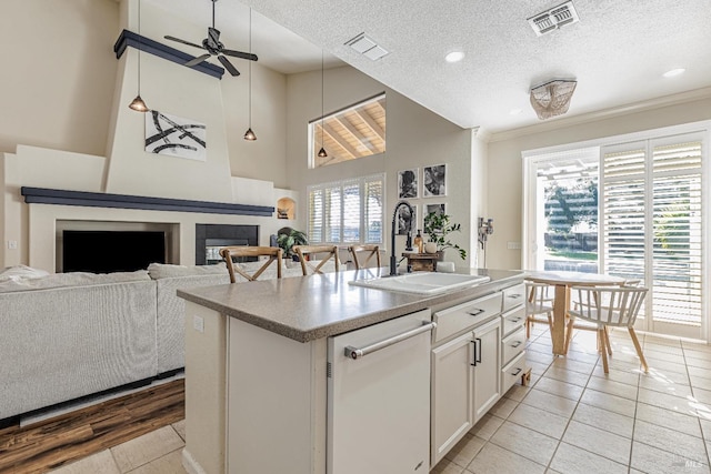 kitchen featuring a large fireplace, visible vents, white dishwasher, and a sink