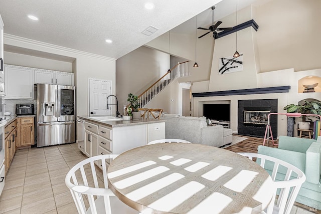 dining room featuring light tile patterned floors, visible vents, stairway, a tiled fireplace, and ceiling fan