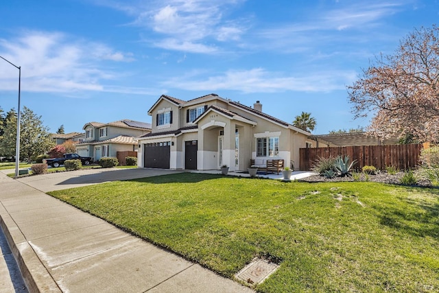 view of front of home with stucco siding, concrete driveway, a front yard, fence, and a garage