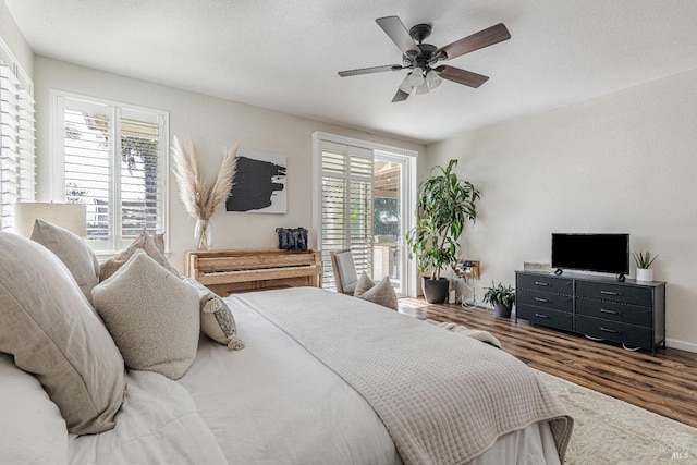 bedroom featuring access to outside, multiple windows, ceiling fan, and wood finished floors