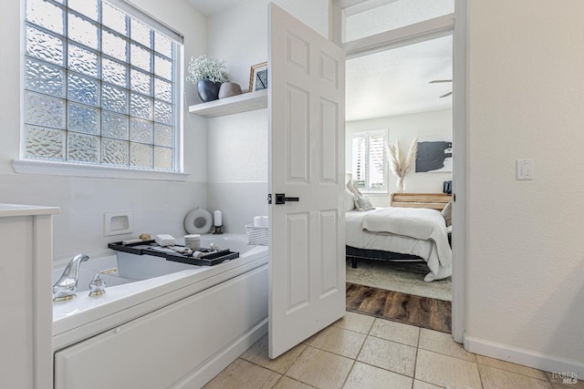 bathroom with connected bathroom, a bath, and baseboards