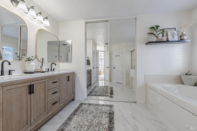 full bathroom featuring marble finish floor, a garden tub, a sink, and double vanity