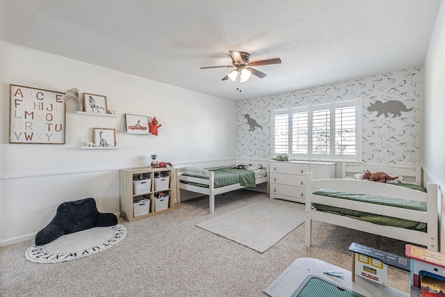 bedroom featuring a textured ceiling, carpet floors, ceiling fan, and wallpapered walls