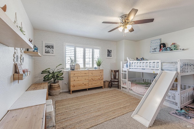 carpeted bedroom with ceiling fan and a textured ceiling