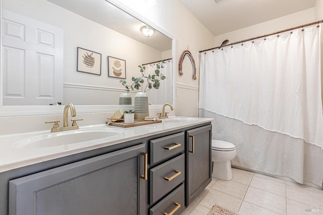 bathroom with double vanity, tile patterned flooring, toilet, and a sink