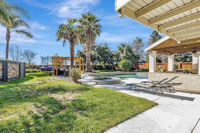 view of yard with a trampoline, a patio area, a fenced backyard, and a pool with connected hot tub