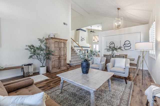 living area with visible vents, wood finished floors, high vaulted ceiling, baseboards, and stairs