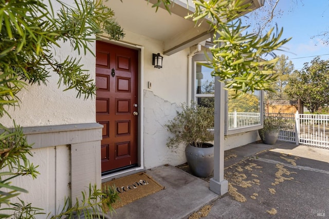 entrance to property with fence and stucco siding