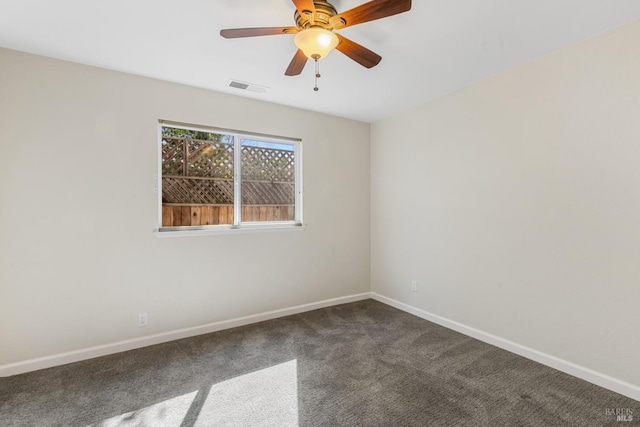 empty room with visible vents, dark carpet, baseboards, and ceiling fan