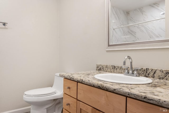 bathroom featuring baseboards, vanity, and toilet