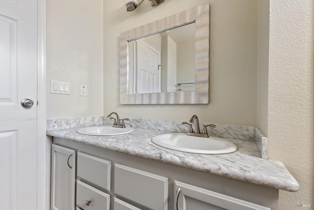 bathroom featuring double vanity, a sink, and a textured wall