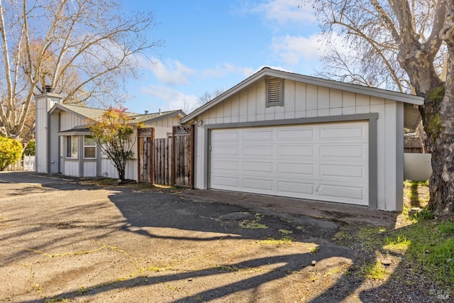 view of front of property with an outbuilding, a chimney, a detached garage, and fence