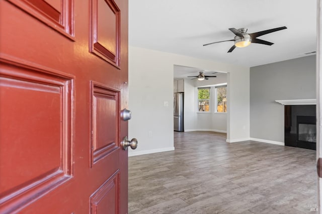 foyer entrance featuring wood finished floors, ceiling fan, baseboards, and visible vents