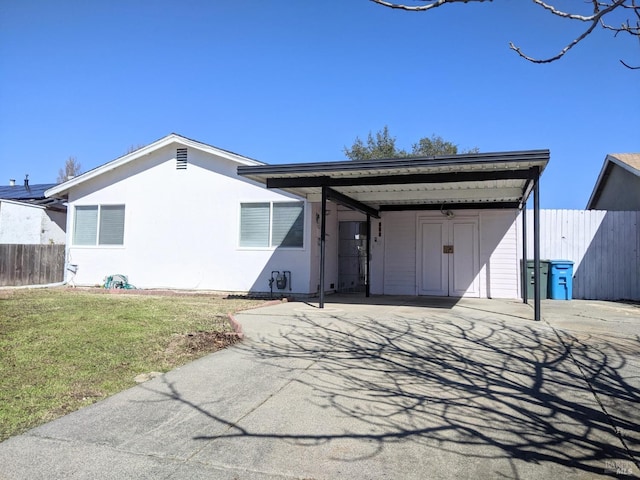 view of front of property featuring fence, driveway, stucco siding, a carport, and a front lawn