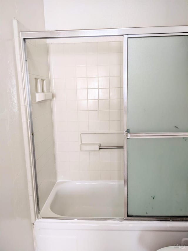 bathroom featuring shower / bath combination with glass door and toilet