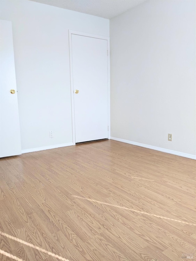 empty room with light wood finished floors and baseboards