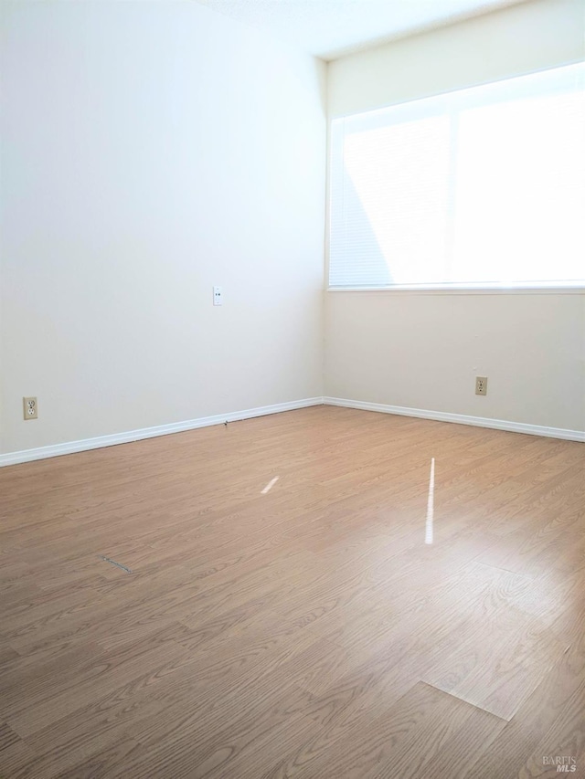 spare room with light wood-style floors and baseboards