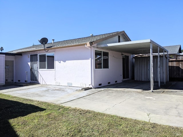 rear view of house with crawl space, fence, an attached carport, and stucco siding