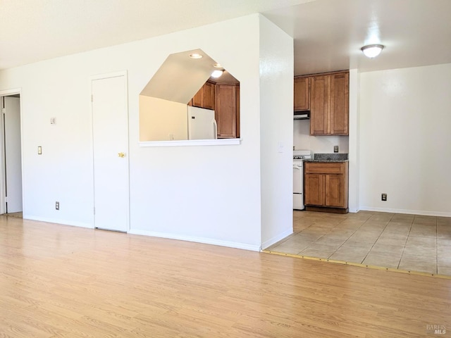 kitchen with brown cabinetry, white appliances, light wood-style flooring, and baseboards