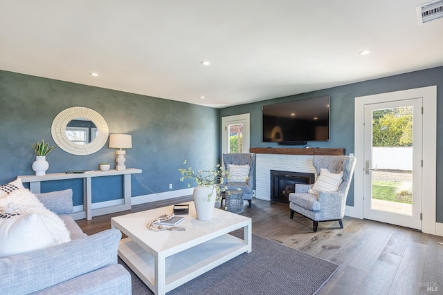 living room with visible vents, a glass covered fireplace, wood finished floors, and recessed lighting