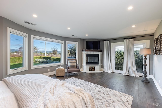 bedroom with visible vents, dark wood finished floors, access to outside, a fireplace, and recessed lighting