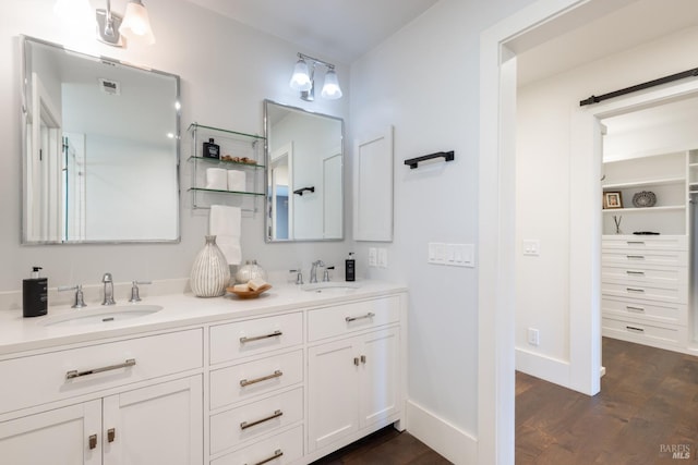 full bath featuring double vanity, baseboards, a sink, and wood finished floors