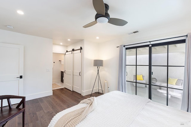 bedroom with a barn door, wood finished floors, visible vents, access to exterior, and baseboards