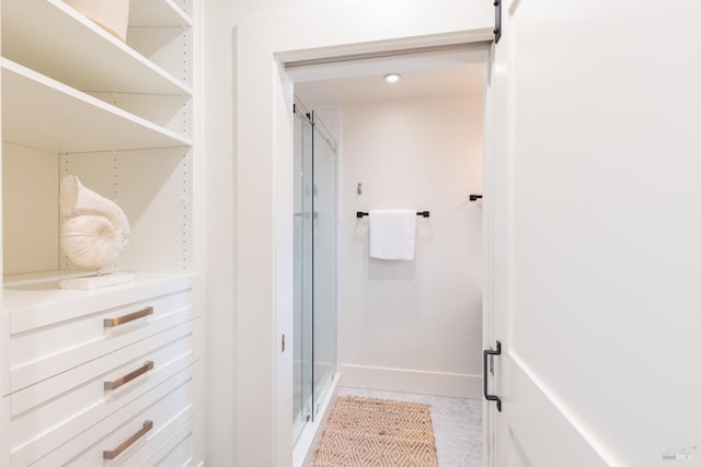 bathroom with a shower stall and baseboards