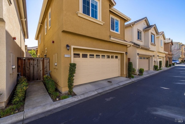 exterior space with an attached garage, a residential view, and stucco siding