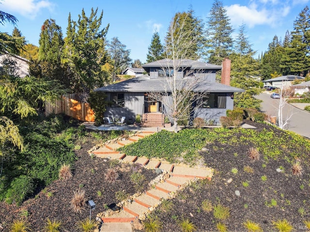 prairie-style home featuring a chimney and fence