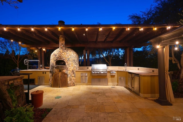 patio at night with grilling area, a fireplace, and area for grilling