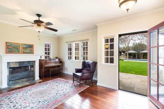 living area with ornamental molding, a fireplace, baseboards, and hardwood / wood-style floors