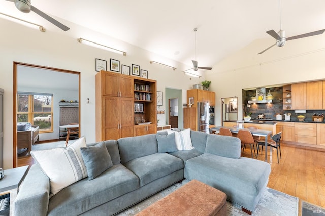 living area featuring lofted ceiling, light wood finished floors, and ceiling fan