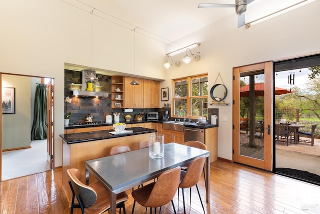 kitchen featuring backsplash, dark countertops, a center island, and wall chimney range hood