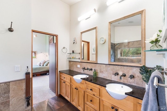 bathroom with ensuite bath, double vanity, backsplash, and a sink