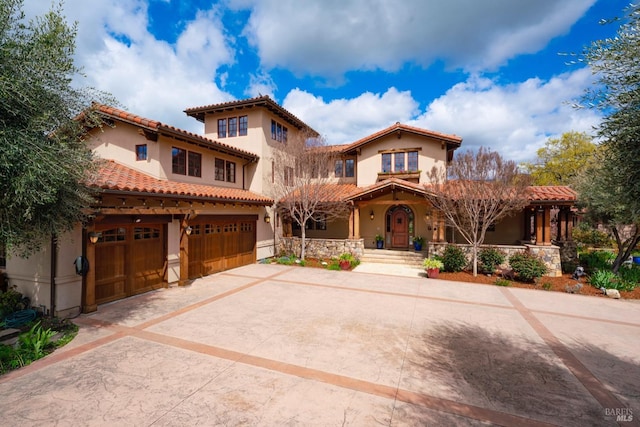 mediterranean / spanish-style house with a tiled roof, stucco siding, an attached garage, and driveway