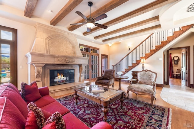 living room featuring stairway, wood finished floors, beamed ceiling, and a premium fireplace