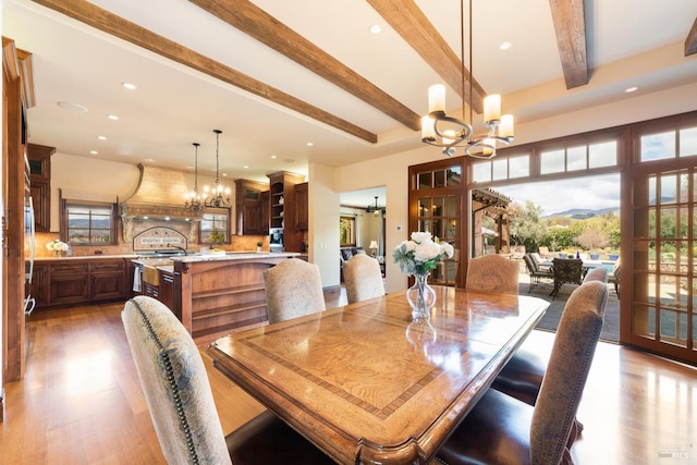 dining space with beamed ceiling, plenty of natural light, and an inviting chandelier