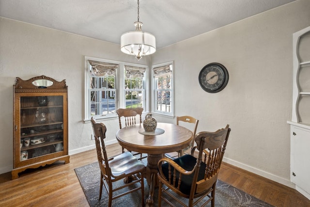 dining area featuring an inviting chandelier, baseboards, and wood finished floors