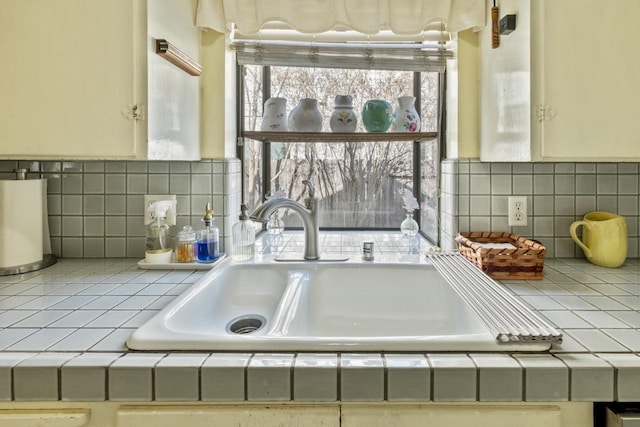 interior details with tile counters, a sink, and tasteful backsplash