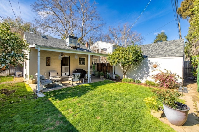 rear view of property with a lawn, a ceiling fan, a fenced backyard, and stucco siding
