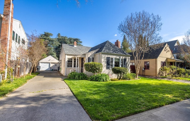 bungalow-style home featuring a chimney, a front yard, a detached garage, fence, and an outdoor structure