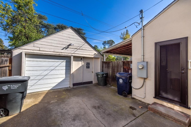 detached garage featuring fence and driveway