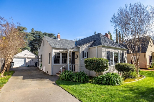 bungalow-style home featuring a garage, a front yard, roof with shingles, a chimney, and an outbuilding